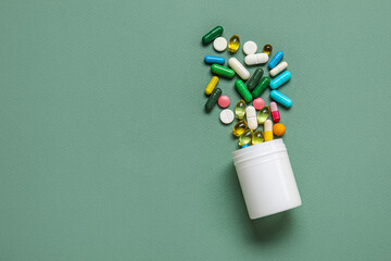 Wall Mural - Jar with different scattered pills on green background