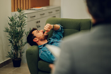 Wall Mural - A depressed man is lying down on a sofa in a psychotherapist's office.