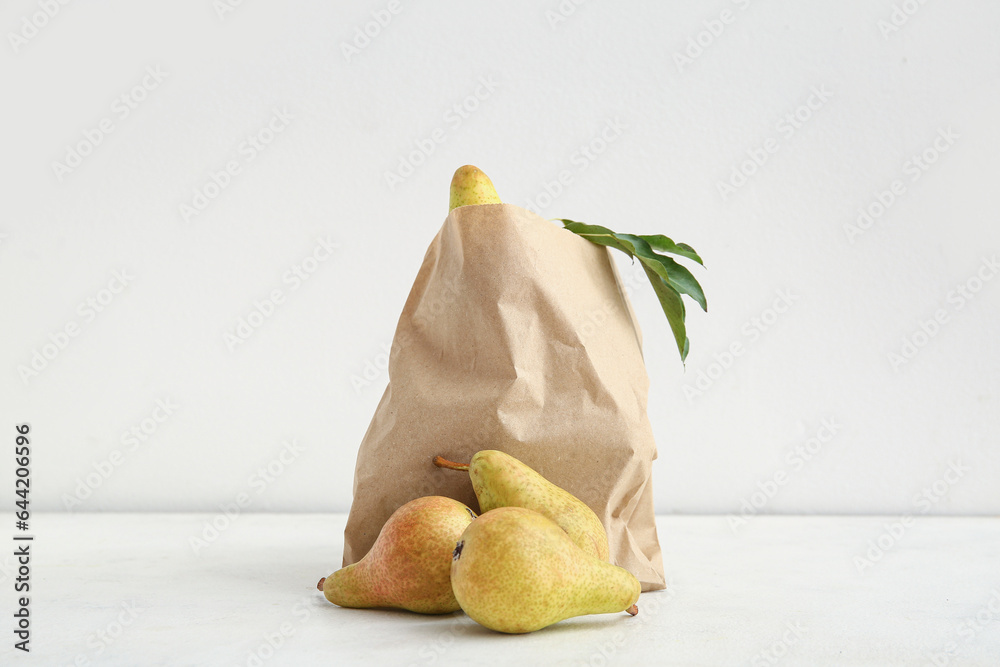 Paper bag with ripe pears on white background