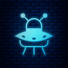 Poster - Glowing neon UFO flying spaceship icon isolated on brick wall background. Flying saucer. Alien space ship. Futuristic unknown flying object. Vector