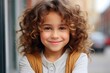 © Irina - Portrait of a happy seven year old girl with curly hair outdoors in the street.