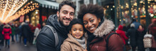 Interracial family smiling in city street with Christmas lights