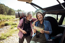 Happy senior couple using a map to navigate themselves in the forest while out camping or hiking