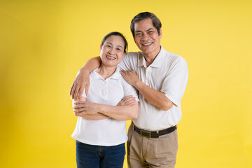 portrait of middle aged asian couple posing on yellow background