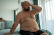 © DimaBerlin - Depressed obese man feels overworked body due to metabolic disorder. Tired fat male puts hand on head suffers chronic fatigue, headaches, dyspnea, increased blood pressure. Eating disorder problem.