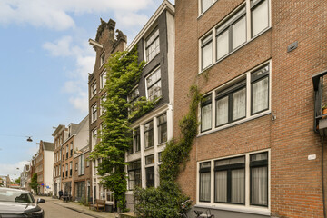 a city street with cars parked on the side and trees growing up the building's sides in the background