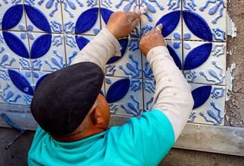 A builder, tiler placing 3 dimension azulejos on adhesive cement, exterior wall, Lagos, Algarve, Portugal, Europe