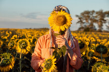 Woman Covering Face With Sunflower Standing In Field