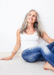 © Westend61 - Contemplative mature woman sitting on hardwood floor at home