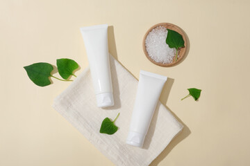 Sticker - Minimal concept for advertising cosmetics with ingredient from fish mint leaf. Two cosmetic tubes mockup for design with white towel, fresh fist mint leaves and wooden tray container bath salt