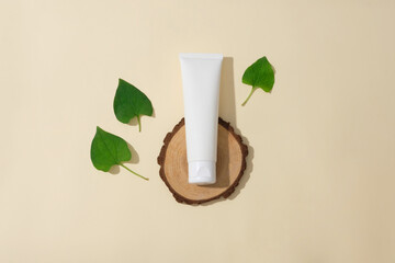 Sticker - Blank plastic cosmetics container for cream of facial cleanser on a wooden podium and fresh fish mint leaves on a beige background. Minimal background with copy space for cosmetics presentation