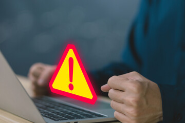 Wall Mural - businessman using laptop showing warning triangle and exclamation sign icon warning of dangerous pro