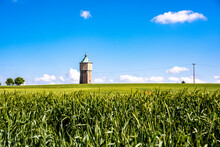 Germany, Baden-Wurttemberg, Crailsheim, Green Springtime Field With Water Tower In Background