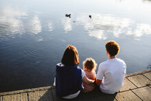 Family Looking At Ducks Swimming In Lake