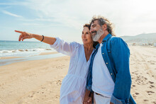 Smiling Woman Gesturing With Man Standing At Beach