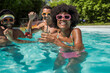 © Westend61 - Cheerful friends enjoying pool party at resort