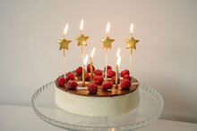 Tempting Cake With Burning Candles On Table In Front Of Wall