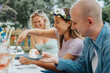 © Maskot - Happy young woman wearing tiara while serving cake to male friend during dinner party at cafe