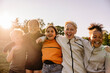 © Maskot - Portrait of cheerful kids with arms around playing together against sky