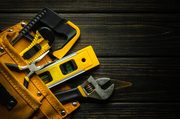 Wall Mural - A set of tools for a master builder in a suede bag on a black vintage table. Free space for text or advertising. Preparation of tools before repair work