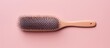 Womens hairstyle seen on a hairbrush against a isolated pastel background Copy space