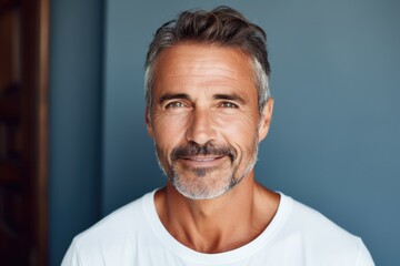 Wall Mural - Portrait of a fifty year old man with a well-groomed face on a blue background. The concept of rejuvenation.