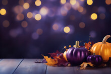 Purple And Golden Pumpkins With Fall Leaves And Decorations On Wooden Ground In Front Of A Bokeh Background With Space For Text