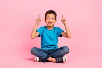 Poster - Full length photo of thoughtful excited small boy wear blue t-shirt looking pointing two fingers up empty space isolated pink color background