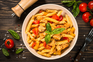 Poster - Pasta with chicken and vegetables at wooden table. Traditional italian food. Top view.