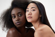 © master1305 - Two beautiful young women, african and asian with well-kept skin, looking at camera against white background. Concept of multi ethnic beauty, natural, spa, cosmetology, wellness, ad