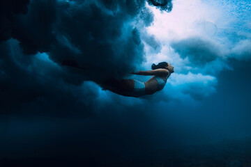 Wall Mural - Woman dive under wave. Duck dive under crashing barrel wave in transparent ocean