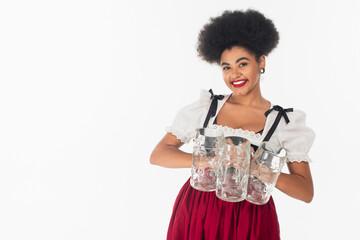 Wall Mural - charming african american bavarian waitress in oktoberfest outfit holding empty beer mags on white