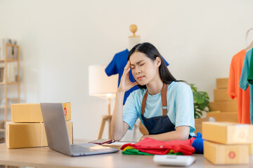 Young Asian woman working at small business ecommerce using laptop stressed and frustrated surprised and angry face. Small online business owner Asian woman stressed headache with parcel box at home.