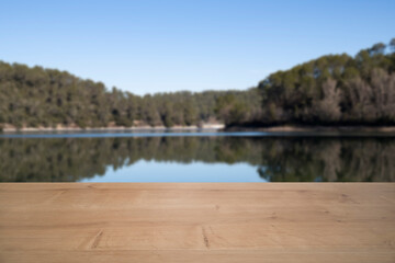  An empty wooden table set against a serene lake and forest backdrop, featuring a picturesque lake. Perfect for showcasing products, advertising, mockups, and more, Copy space for text or titles