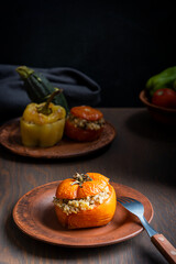 Wall Mural - Homemade juicy organic tomato stuffed with rice and baked until soft served on plate with fork on dark brown wooden table as part of gemista traditional greek recipe of filled roasted vegetables