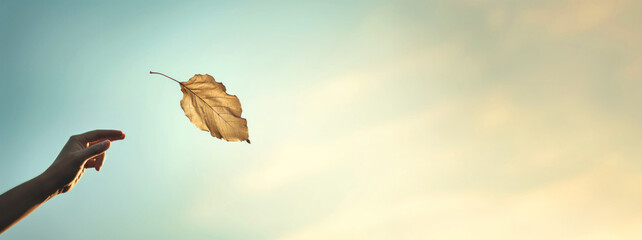 Autumn mental health. Embracing Change: person releasing Autumn falling leaf into the wind, signifying letting go and embracing transitions