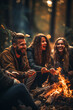Two women and a man friends have fun, spending time together in the autumn forest near a burning fire, talking and laughing. Friendship, travel and autumn hobby concept. Vertical
