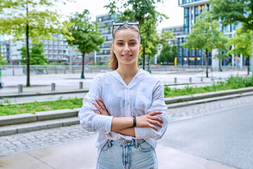 Wall Mural - Portrait of teenage girl with crossed arms on street of city