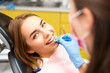 © vladim_ka - A dentist instructs a young woman on the correct technique for using dental floss