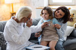 © ArtSys - Concept healthcare medical assistance, insurance. Kind senior female paediatrician doctor examining little child sitting on mother's laps, during home visit or clinic check up. Prescribing treatment