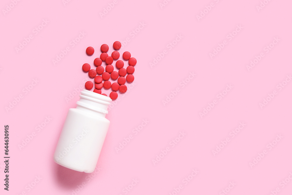 Jar with scattered pills on pink background