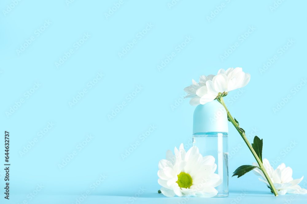 Bottle of deodorant with chamomile flowers on color background
