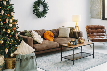 Christmas background of livingroom, background. Baubles and wreath by sofa in golden and green color. Decorated New Year room interior, Copy space. 