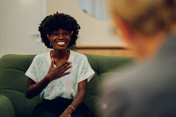 Wall Mural - A happy african american woman is sitting at the psychotherapist's office and discussing her progress with a therapist.