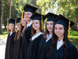 © Михаил Решетников - Row of happy young people in graduation gowns outdoors. Students in the park.