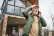 © Miljan Živković - angry senior man stand in front of tiny house in day use smart phone