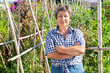 Portrait of happy smiling elderly woman in her vegetable garden on sunny fall day