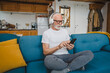 © Miljan Živković - one senior man with headphones use smsrtphone to play music at home