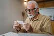 © Miljan Živković - One man senior caucasian male hold medicine drugs tablet read label