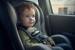 Adorable little girl sitting in the back seat of a car. Child toddler boy sitting in a car in the back seat in a child car seat. Happy kid in a child car seat wearing a seatbelt while traveling by car